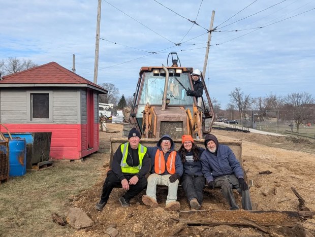 Fox Valley Trolley Museum volunteers Andrzej Jurek, from left, Dave Peterson, Joe Caliendo, Kathleen Jamieson and Mike Gilles take a break sitting on the tractor that was used to move wooden rail ties as they prepare to expand the museum's storage barn. (James Tarbet)