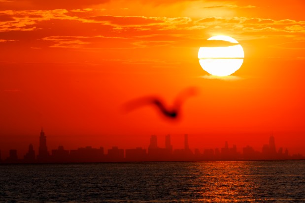 The sun sets behind the Chicago skyline as seen from the Indiana Dunes National Park, May 30, 2023, in Michigan City, Indiana.