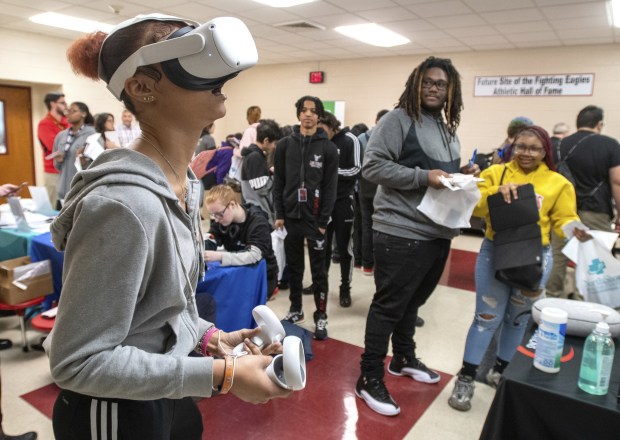 Thomas A. Edison Junior Senior High School senior Mikaylah Baber, 17, uses a virtual reality headset as her friends Dante Taylor, left, and Aliyah Lawson look on during the "Bridging the Gap in a Diverse World" program for juniors and seniors at the school in Lake Station, Indiana Tuesday March 21, 2023. (Andy Lavalley for the Post-Tribune)