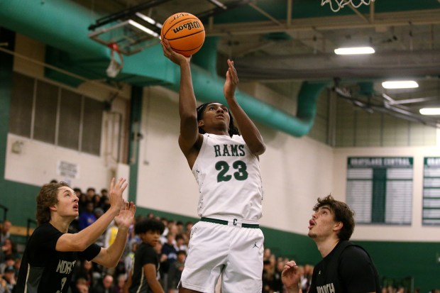 Grayslake Central's Chris Jaimes (23), putting in a jumper after getting through Grayslake North's Brady Ballentine (left) and Uros Mitrovic (right), during the game on Friday, Dec. 6, 2024.  (Mark Ukena/for the Lake County News-Sun)