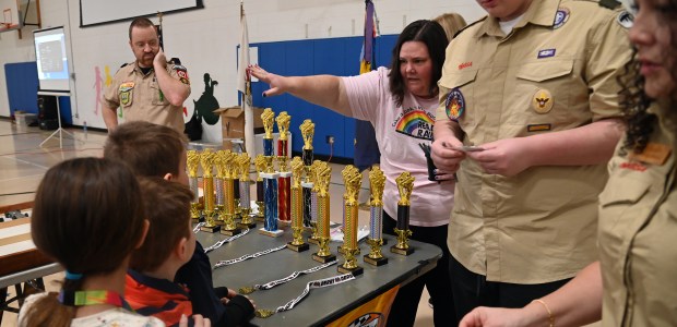 In pink shirt, pointing, at Scout judging time is volunteer Rebecca Daugherty of Grayslake at the Cub Scout Pack 627 of Gurnee Pinewood Derby on Jan. 26, 2025 in the gym at Woodland Elementary School in Gages Lake. (Karie Angell Luc/Lake County News-Sun)