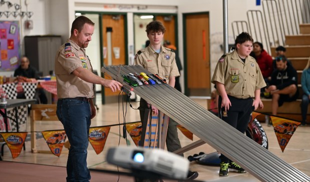 Left, Chris Lepley of Gurnee helps to release a heat of cars at the Cub Scout Pack 627 of Gurnee Pinewood Derby on Jan. 26, 2025 in the gym at Woodland Elementary School in Gages Lake. (Karie Angell Luc/Lake County News-Sun)