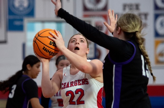 Naperville Central's Tessa Williams (22) shoots a layup while being covered by Hampshire's Autumn Kriegel (13)...Naperville Central (wearing borrowed jerseys) were defeated by Hampshire 58-53 in overtime on the fourth day of the Dundee-Crown's Komaromy Classic, Monday, Dec. 30, 2024 (Rob Dicker / for the Naperville Sun)