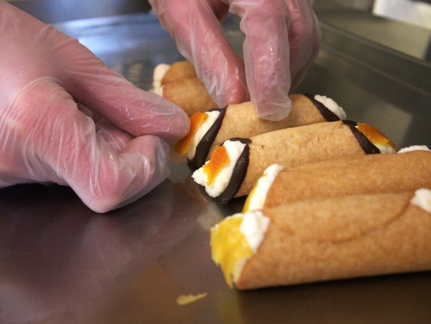 Tony Volpentesta adds the finishing touches to a row of cannolis at his pastry shop Tony Cannoli. Volpentesta learned how to make cannoli from his Italian grandmother. (Joe States/Lake County News-Sun)