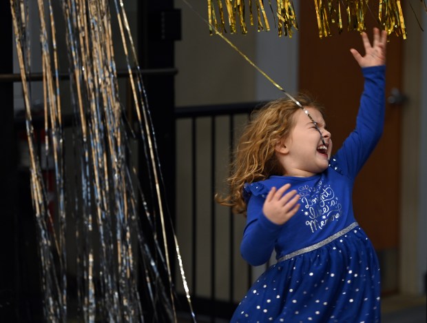 Showing joy with the shimmering doorway streamers is Maggie Bernstein, 6, a kindergartner from Deerfield, entering the gym at Noon Year's Eve on Dec. 31, 2024 in Deerfield at Sachs Recreation Center. (Karie Angell Luc/Pioneer Press)