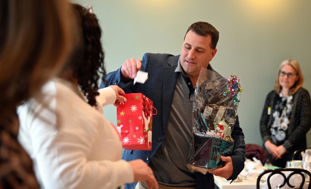 Right, Ed Beauvais, Maine Township highway commissioner and an incoming chamber board member, takes a winning name from a bag to award a hospitality gift basket at the Park Ridge Chamber of Commerce's Holiday Tea Party at TeaLula in Park Ridge on Dec. 18, 2024. (Karie Angell Luc/Pioneer Press)