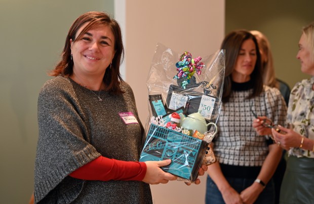 Left, Simona Pappalardo of Niles, a personal development coach, is the winner of this gift basket presented by (unseen) Ed Beauvais, Maine Township highway commissioner and an incoming chamber board member, at the Park Ridge Chamber of Commerce's Holiday Tea Party at TeaLula in Park Ridge on Dec. 18, 2024. (Karie Angell Luc/Pioneer Press)