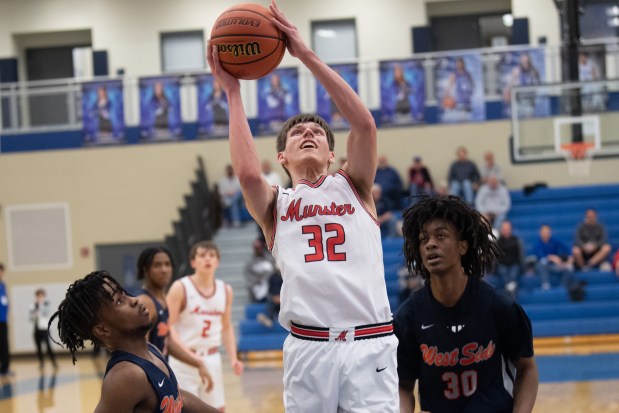 Munster's Brandon Trilli, center, takes the ball to the basket against West Side's Israel Hines, left, and KeiShawn McLaurin during a game in the first round of the Class 4A Lake Central Sectional in St. John on Wednesday, March 2, 2022. (Kyle Telechan / for the Post-Tribune)