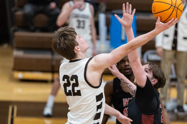 Mount Carmel's Eddie Ryan (22) puts the ball in from behind the backboard against Eisenhower during a nonconference game in Chicago on Monday, Jan. 6, 2025. (Vincent D. Johnson / for the Daily Southtown)