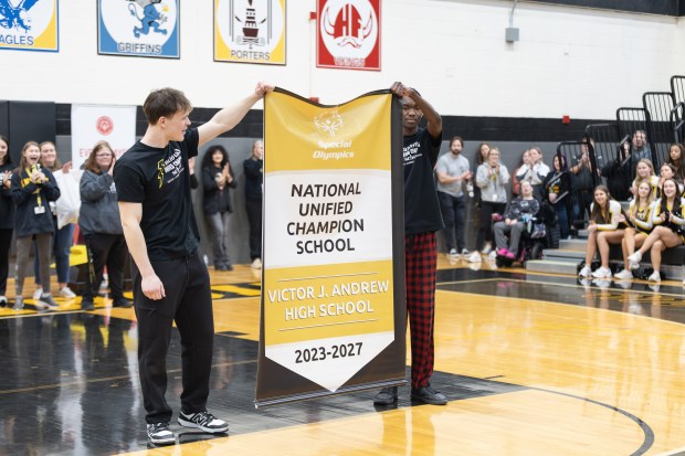 Andrew High School seniors Scott Oftedahl, left, and Montrell Sippel hold a banner during Friday's all-school assembly recognizing the school's National Unified Champion Banner status. (Troy Stolt/for the Daily Southtown)