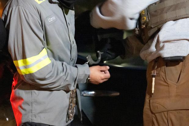 U.S. Immigration and Customs Enforcement officers use a chain to more comfortably restrain a detained person using handcuffs positioned in front, Monday, Jan. 27, 2025, in Silver Spring, Md. (AP Photo/Alex Brandon)