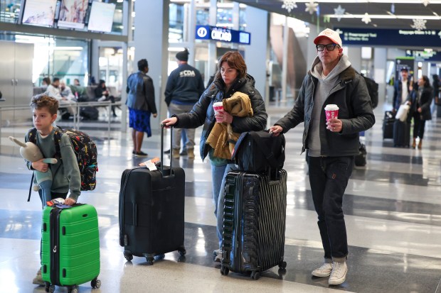 Kristen, center, and Stacy Jones leave with their son, Waylon, from the baggage claim area in Terminal 3 at O'Hare International Airport on Jan. 9, 2025 after arriving on a flight from from LA. They delayed their planned flight a day because they felt like they couldn't leave when scheduled with the chaos of the fire. (Eileen T. Meslar/Chicago Tribune)