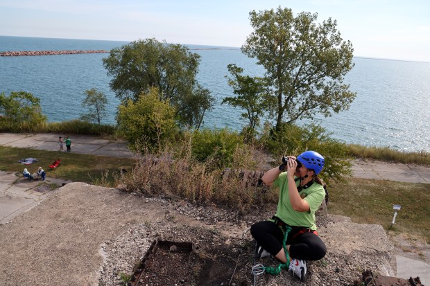 After scaling a climbing wall, birder Sarah Anderson looks for hawks at Steelworkers Park in Chicago, Sept. 13, 2024. (Antonio Perez/Chicago Tribune)