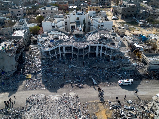 A drone photo shows Palestinians walking through the destruction left by the Israeli air and ground offensive near Al Najjar hospital in Rafah, as a ceasefire deal between Israel and Hamas went into effect, in Rafah, Gaza Strip on Jan. 19, 2025. (Jehad Alshrafi/AP)