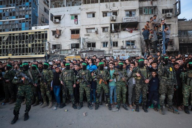 Fighters from the Qassam Brigades, the military wing of Hamas, control the crowd as Red Cross vehicles manoeuvre to collect Israeli hostages to be released under a ceasefire agreement between Israel and Hamas, in Gaza City on Jan. 19, 2025. (Abed Hajjar/AP)