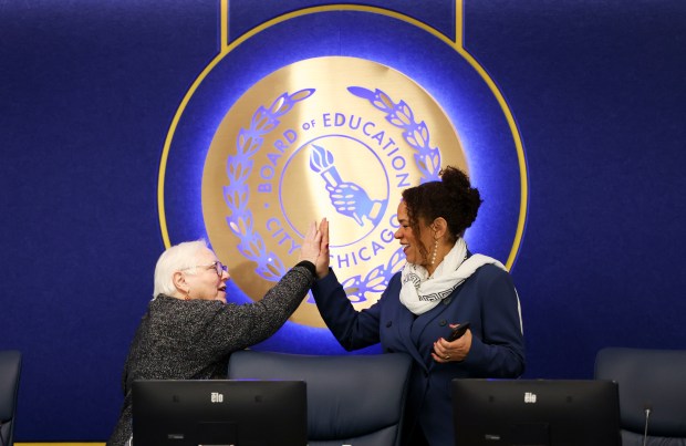 Chicago Public Schools board member Debby Pope high-fives board member Michilla Blaise during a recess in the Chicago Board of Education meeting on Jan. 15, 2025. (Eileen T. Meslar/Chicago Tribune)