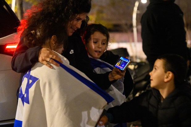 A family gather around a mobile phone to watch footage of the released hostages ahead of their arrival at Sheba Medical Center, also known as Tel HaShomer Hospital, where hostages are arriving after the first phase of a ceasefire agreement began between Israel and Hamas on Jan. 19, 2025, in Ramat Gan, Israel. (Alexi J. Rosenfeld/Getty)