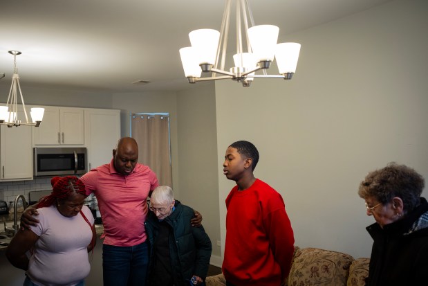 Sister Pat Murphy, center, and Sister JoAnn Persch, right, pray with Zuleika del Carmen Valencia cox de Appleton, from left, Oscar Alfonso Appleton and their son Josafat Keileb Appleton Valencia, 14, during a visit the nuns made to the family of migrants from Panama, Jan. 11, 2025. (E. Jason Wambsgans/Chicago Tribune)