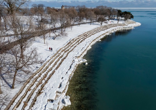 People walk in the snow near the limestone rocks at Promontory Point along Lake Michigan on Jan. 14, 2025. (Brian Cassella/Chicago Tribune)