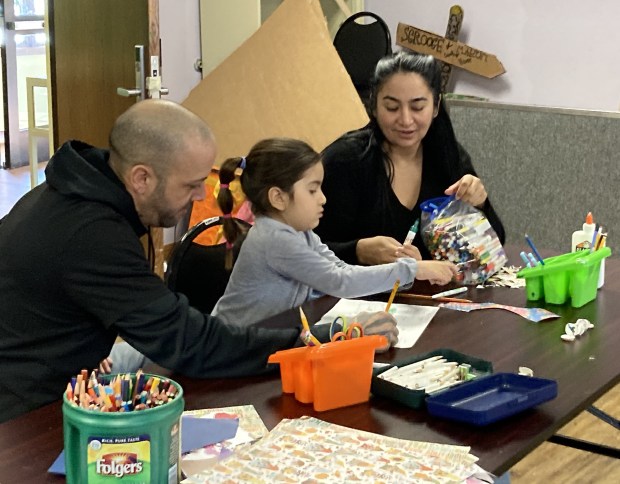 Shannon Smith, left, looks at Amy Rosado's button book as Amy and her mother, Angelica Galeano, watch. (Steve Sadin/For the Lake County News-Sun)