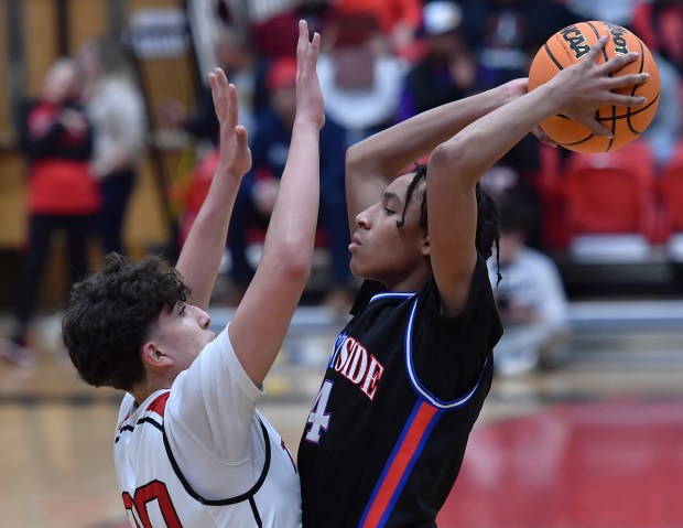 West Aurora's Antonio Higgins (right) starts to pass over East Aurora's Anthony Chavez during a game on Friday, Feb. 7, 2025 in Aurora...(Jon Cunningham/for The Beacon-News)