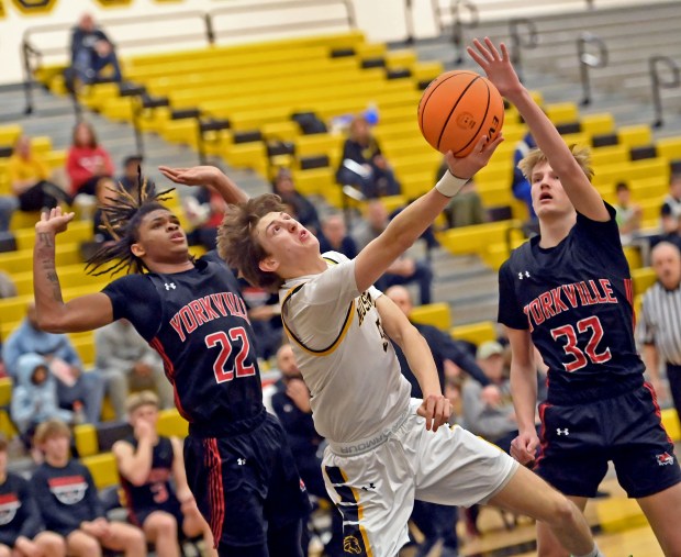 Metea Valley's Jake Nosek splits the defense of Yorkville's Braydon Porter and Joey Jakstys as he drives to the basket. Yorkville defeated Metea Valley in a boys basketball game 66-58 Tuesday, Feb. 11, 2025, in Aurora, Illinois. (Jon Langham/for the Beacon-News)