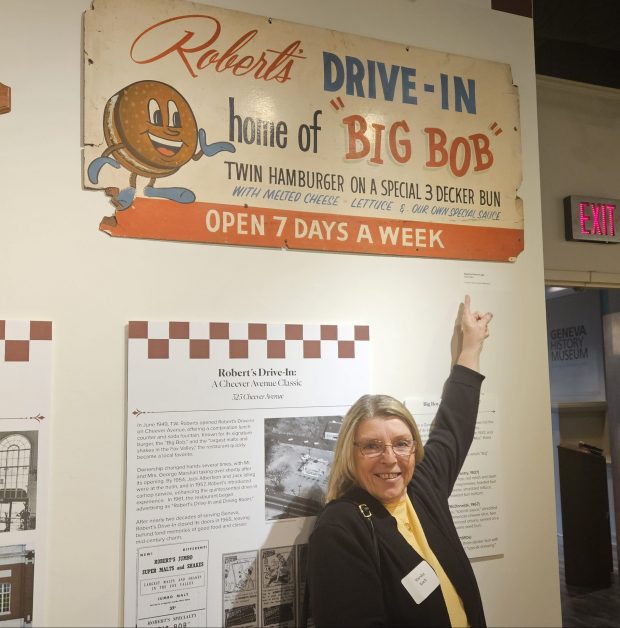 Marsha Koch shows off the sign she and her family donated to the Geneva Historical Museum's new exhibit highlighting the history of restaurants in Geneva. (David Sharos / For The Beacon-News)