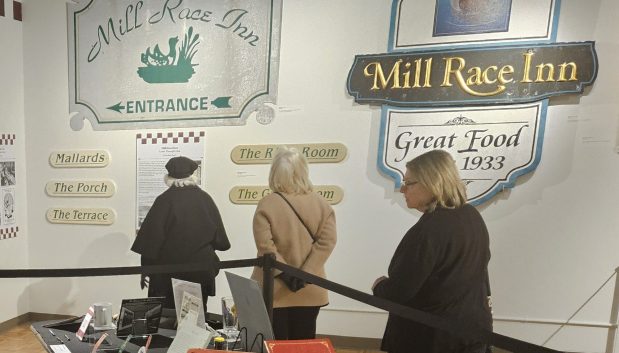 Visitors to the Geneva History Museum look over information about the former Mill Race Inn, which was an iconic restaurant in Geneva for decades. The museum has an exhibit on display showcasing the city's restaurant history. (David Sharos / For The Beacon-News)