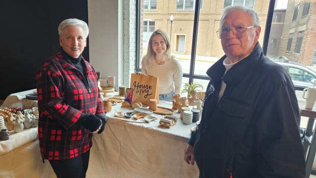 Mary Lou Ruder of Sugar Grove, left, and her husband Wayne stop to see House of Ivy owner Chelsie Kliese of Aurora and check out her pottery Saturday at the indoor market held at Society 57 in downtown Aurora. (David Sharos / For The Beacon-News)