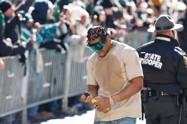 Eagles edge rusher Nolan Smith Jr. pops some champagne on Broad Street during the Super Bowl victory parade. (Monica Herndon/The Philadelphia Inquirer)