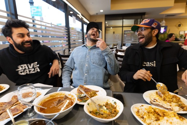 Actor Saagar Shaikh, left, eats dinner with "Deli Boys" creator and Executive Producer Abdullah Saeed, center, and co-star Asif Ali at Ali's Nihari & BBQ in the West Ridge neighborhood on March 31, 2024. (Talia Sprague/for the Chicago Tribune)