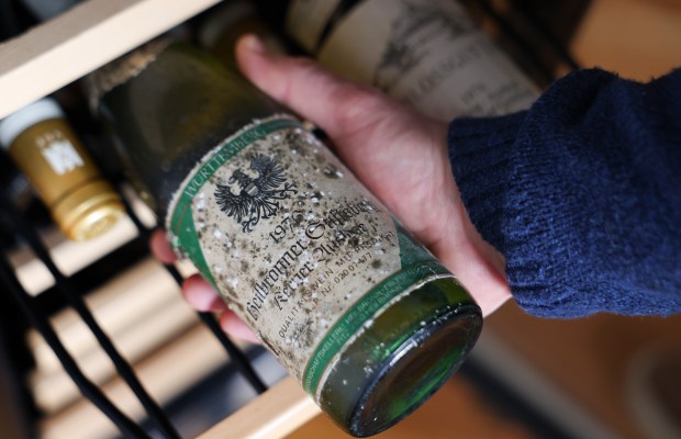 Jesse Becker holds a bottle of 1976 Genossenschaft Heilbronn Heilbronner Stiftsberg Kerner Auslese from Württemberg Germany at his home on Feb. 7, 2025. (Stacey Wescott/Chicago Tribune)