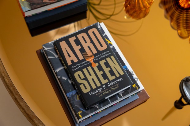 George E. Johnson's memoir sits on the coffee table in his Chicago home, Feb. 18, 2025. It's called "Afro Sheen: How I Revolutionized an Industry with the Golden Rule, from 'Soul Train' to Wall Street." (Brian Cassella/Chicago Tribune)