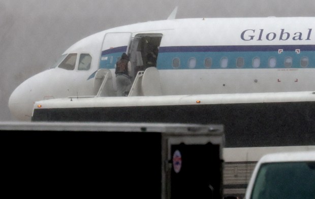 Under heavy rain, people are lead onto a plane at Gary/Chicago International Airport, on Jan. 31, 2025, for deportation. A bus left the Broadview U.S. Immigration and Customs Enforcement center in Broadview early morning and dropped off individuals for deportation at the airport. (Antonio Perez/Chicago Tribune)