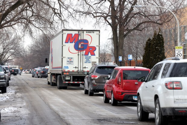 A truck moves along slowly near the school, as several other vehicles line up to drop off children at the school, along St. Louis Avenue on Feb. 14, 2025. (Antonio Perez/Chicago Tribune)