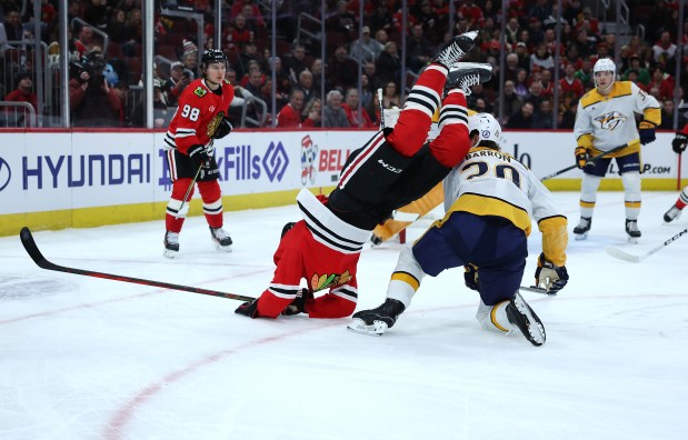 Chicago Blackhawks center Ryan Donato (8) hits the ice after falling over Nashville Predators defenseman Justin Barron (20) in the first period of a game at the United Center in Chicago on Feb. 7, 2025. (Chris Sweda/Chicago Tribune)