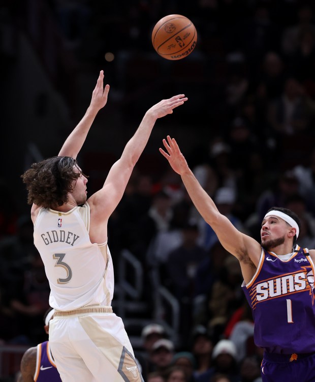 Bulls guard Josh Giddey, left, shoots over Suns guard Devin Booker on Feb. 22, 2025, at the United Center. (Chris Sweda/Chicago Tribune)