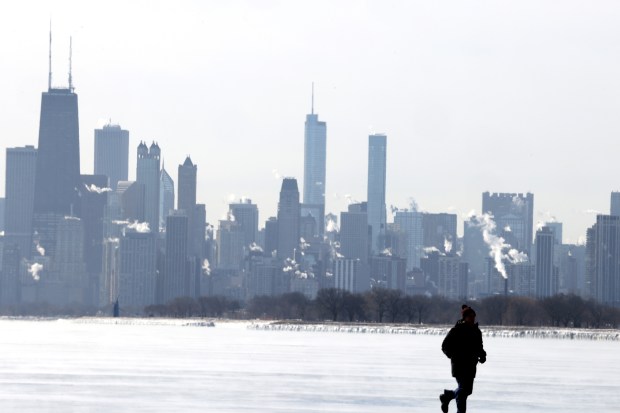 A person at the lake front hurries back to his vehicle after looking over the frozen lake Michigan and Chicago skyline at Montrose Beach on Feb. 18, 2025, as Chicago and the surrounding areas remained under a cold weather until noon on Tuesday. (Antonio Perez/Chicago Tribune)