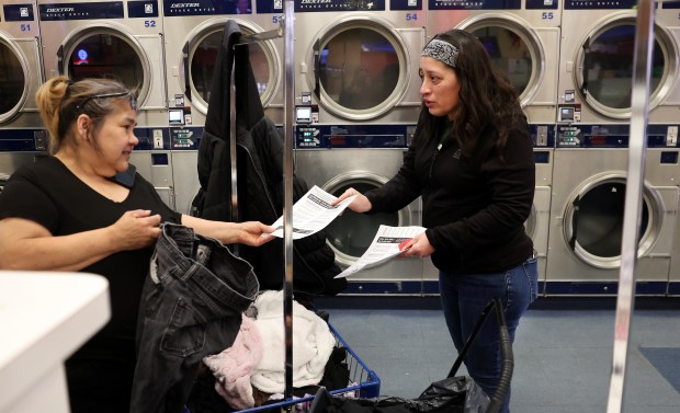 Luz Chavez, right, hands out "Know Your Rights" information to a woman in a laundry as Chavez and three volunteers leaflet businesses along Cermak Road in Berwyn on Jan. 30, 2025. (Chris Sweda/Chicago Tribune)