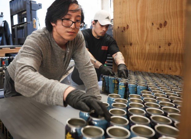 Kevin Liao, left, and Tyler Dierkes stack freshly labeled aluminum cans onto a pallet at BevWrap on Feb. 20, 2025, in Elk Grove Village. BevWrap can steam wrap labels on up to 38,400 cans a day. (Stacey Wescott/Chicago Tribune)