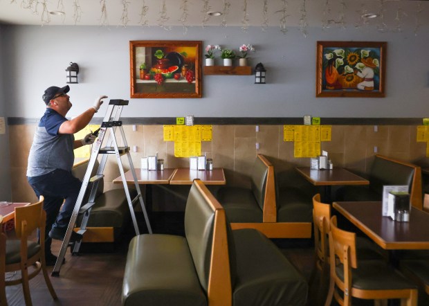 Adolfo "Junior" Bello climbs a ladder to do some work around his restaurant after closing El Faro today in solidarity with the Day Without Immigrants action on Feb. 3, 2025, in Elgin. (Stacey Wescott/Chicago Tribune)