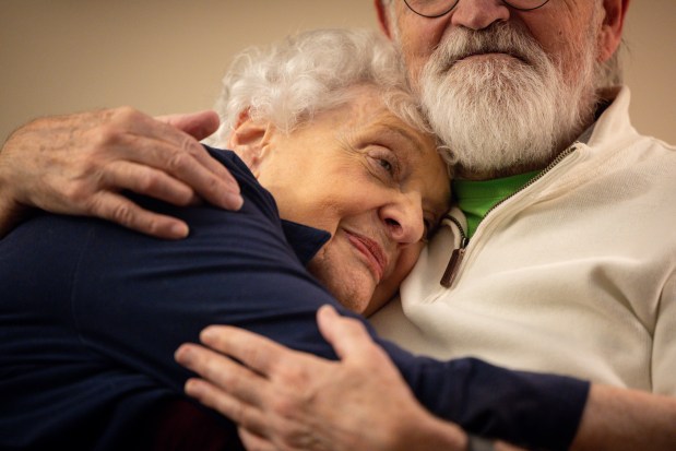 Sanna Longden and Clint Seely hug on the couch in their apartment at The Mather before heading to a show at Northwestern University, Jan. 31, 2025. (Audrey Richardson/Chicago Tribune)