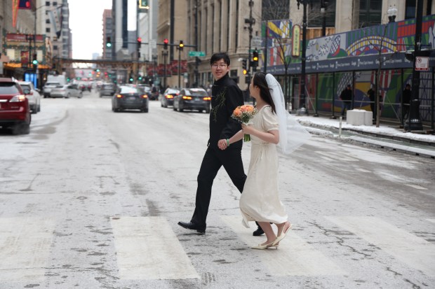 Yuming Shi and Wihan Yang pose for photos for a photographer after exchanging wedding vows on Valentines Day at City Hall, Feb. 14, 2025. (Antonio Perez/Chicago Tribune)