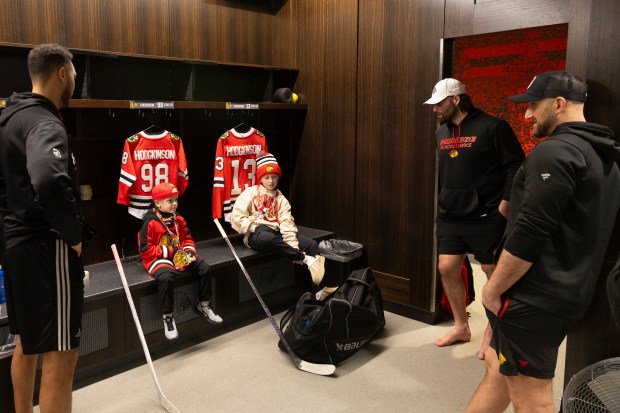 Lennox Hodgkinson, 7, left, and brother King, 11, of Nova Scotia, talk with Chicago Blackhawks players in the United Center locker room after morning skate on Wednesday, Feb. 5, 2025, at the United Center. Lennox Hodgkinson, who has cystic fibrosis, was invited to join the Blackhawks as part of the team's partnership with the Make-A-Wish Foundation. (Chicago Blackhawks photo)