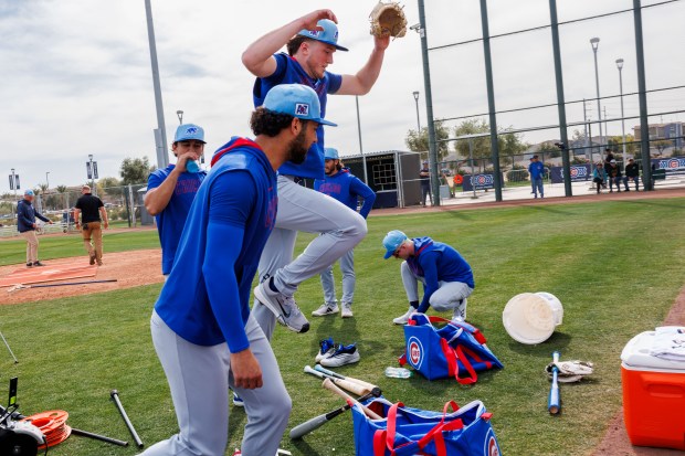 Cubs pitcher Gavin Hollowell jumps over a bag while center fielder Pete Crow-Armstrong puts on his cleats during spring training on Feb. 13, 2025, at Sloan Park in Mesa, Ariz. (Armando L. Sanchez/Chicago Tribune)