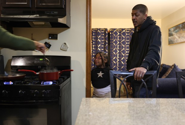 Donnell Dubose talks with his wife, Rachel, as she cooks dinner for their family, including her daughter, Kaysey, 6, at their home, Feb. 18, 2025, in Sauk Village. (John J. Kim/Chicago Tribune)