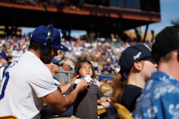 Brandon Collins, 39, cleans his daughter Kennedy Collins, 3, face while watching the Chicago Cubs play the Los Angeles Dodgers during the third inning at spring training at Camelback Ranch Thursday Feb. 20, 2025, in Glendale, Arizona. (Armando L. Sanchez/Chicago Tribune)