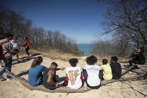 Fegely Middle School eighth-graders rest on a log and take in the view after tackling the second of three dunes in the 3 Dune Challenge during a field trip to the Indiana Dunes State Park on Wednesday, April 12, 2023. (Kyle Telechan for the Post-Tribune)