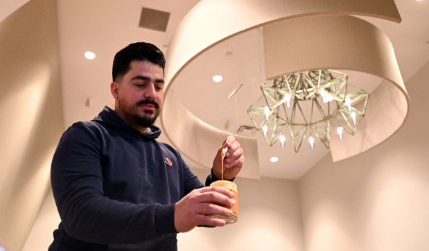 Vendor Patrick Rahy of Streamwood and of Albaik Honey Tahini of Arlington Heights shows a honey infused product at the Indoor Winter Ravinia Farmers Market on Feb. 15, 2025 in Highland Park at the Wayfarer Theaters. (Karie Angell Luc/Lake County News-Sun)