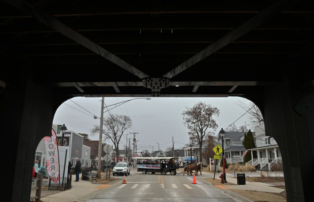 The horse-drawn carriage is seen through the view of Robert Parker Coffin Road Bridge during the Cocoa Crawl in downtown Long Grove on Feb. 8, 2025. (Karie Angell Luc/Lake County News-Sun)